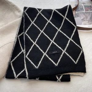 Close-up of diamond pattern knitted scarf with brand label and wool texture detail