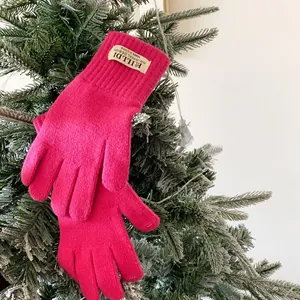 Close-up of pink knitted touchscreen gloves hanging on a festive Christmas tree branch