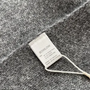 Detail of wool blend knit texture and product care label on a soft grey winter neck warmer