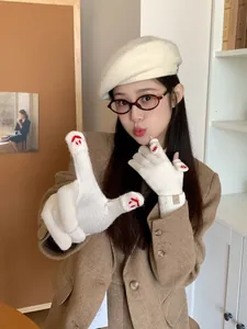 Close-up of beige knitted gloves with red smiley face embroidery and K-RET brand label