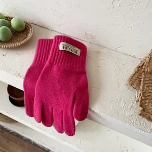 Detail of rose pink knit gloves with ribbed cuffs and original woven brand labels