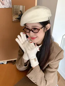 Detailed shot of cream knitted glove featuring a red heart embroidery on the fingertip