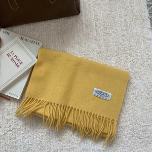 Gros plan d'une écharpe en laine jaune avec de longues franges et une étiquette blanche