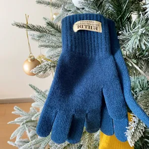 Close-up of navy knit gloves with ribbed cuffs hanging on a festive Christmas tree branch