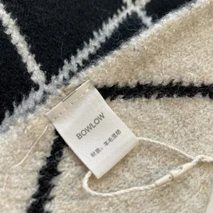 Close-up of black and white check wool blend scarf fabric texture and branded label