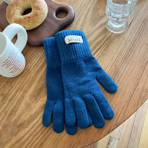 Detail of dark blue knitted touchscreen gloves with ribbed cuffs on a wooden table