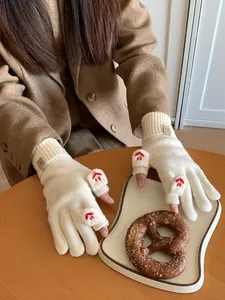 Close-up of beige knit fingerless gloves with plush details and red star embroidery accents