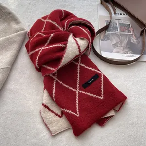 Detailed view of the thick red argyle wool scarf texture with a sewn black brand label