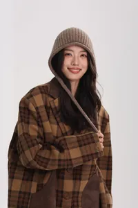 Close-up of brown wool knit beanie earflap hat paired with vintage plaid coat sleeve