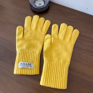 Detail of yellow knit gloves with touch screen finger opening on a wooden background