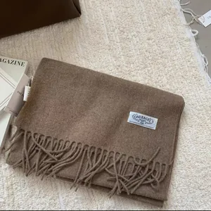 Détail de l'écharpe en laine avec franges et étiquette tissée sur fond doux