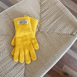 Detail of yellow knitted gloves with ribbed cuffs and original design logo tag