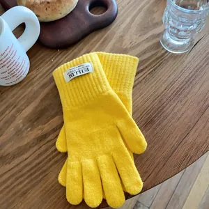 Detail of bright yellow knit gloves on a wooden table for a cozy winter aesthetic