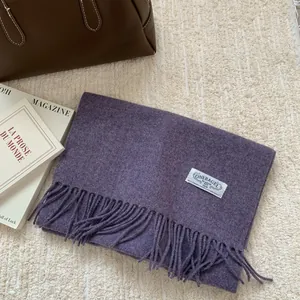 Gros plan sur l'écharpe en laine violette avec franges et étiquette de la marque