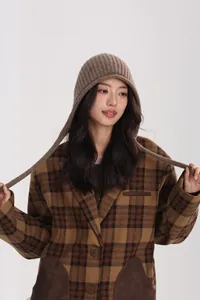 Detailed texture of brown knit wool earflap hat paired with vintage plaid coat