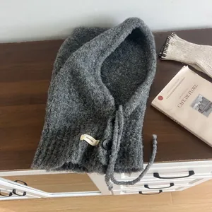 Detailed close-up of dark grey wool blend knitted balaclava with button and drawstring