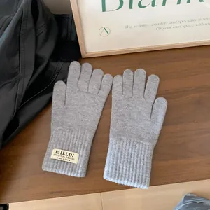 Detailed view of light gray knitted gloves featuring ribbed cuffs and woven brand labels