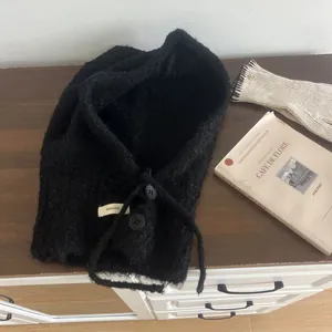 Detail of black fleece balaclava with buttons and drawstrings on wooden surface