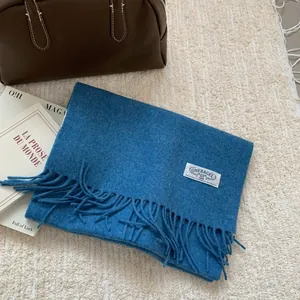 Détail d'une écharpe en pure laine bleu clair avec franges et étiquette de marque