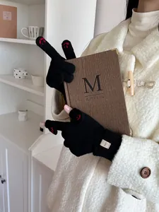 Detail of black knitted gloves featuring red paw embroidery and an ERET logo tag