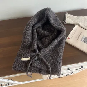 Close-up of wool blend balaclava with knit texture and dual button closure on wood