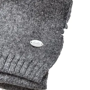 Close-up of grey knit scarf with ribbed edge and elegant silver brand logo plaque