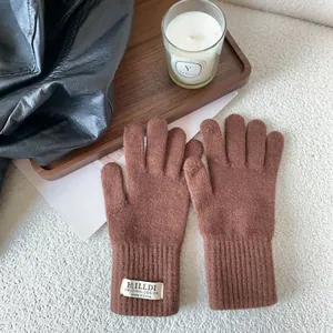 Detailed knit texture of coffee brown winter gloves with ribbed cuffs and woven brand label