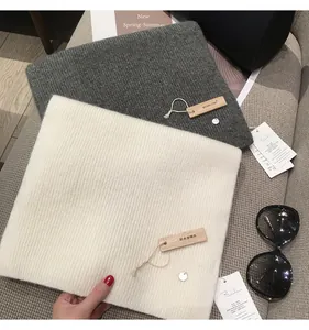 Detailed view of gray and beige ribbed knit scarves with wooden tags and accessories