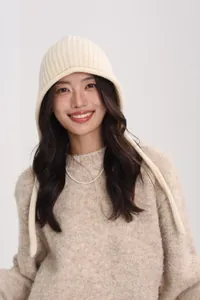 Detail of cream wool knitted earflap hat with vertical textures and long chin ties