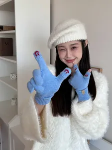 Detail of blue knitted gloves with red smiley embroidery and ribbed cuffs for winter warmth