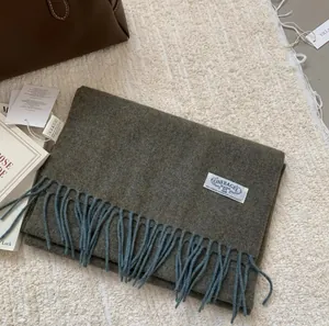 Détail de l'écharpe en laine à franges avec étiquette de marque sur surface tricotée