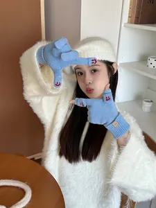 Close-up of blue knitted fingerless gloves with red smile design and a small label