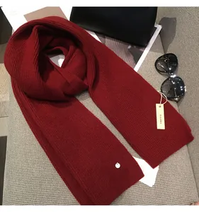 Detail of dark red ribbed knit scarf with fashion accessories and lifestyle props