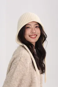 Detail of off-white wool knit beanie featuring ribbed texture and earflaps with long straps