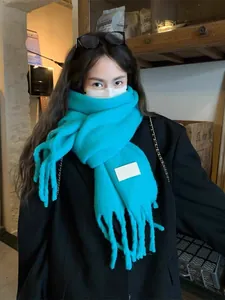 Detailed view of bright teal knitted scarf featuring thick fringe tassels and soft cashmere-like texture
