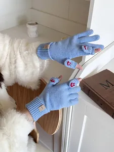 Close-up of light blue convertible knit gloves with a red embroidered smiley face design