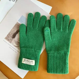 Detail of green knitted touchscreen gloves with ribbed cuffs on a wooden background