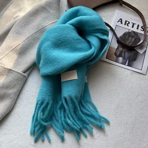 Thick teal cashmere-like scarf with fringe and a small woven label for autumn and winter