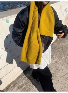Détail de l'écharpe en laine jaune vif avec grosse maille et motif de losanges tressés