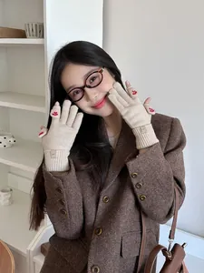 Close-up of beige knit gloves featuring red clover embroidery and EAST cloth label