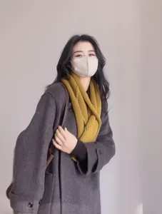 Détail de l'écharpe en laine jaune vif associée à un manteau gris et un masque beige