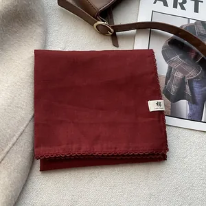 Foulard quadrato in cotone rosso scuro con pizzo mostrato su sfondo lifestyle elegante