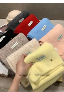 Close-up of stacked wool blend knit scarves in various cream and pastel colors