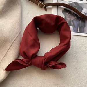 Bandana in cotone rosso scuro con design annodato su sfondo di rivista di moda