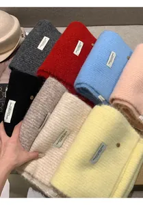 Close-up of thick wool knit scarves in multiple colors with rectangular fashion labels