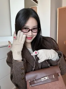 Detail of cream knitted gloves with flip-top fingers and cute red smiley face embroidery