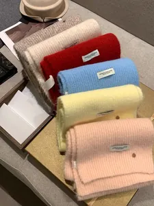 Macro detail of multi-colored rib-knit wool scarves with minimalist fashion fabric labels