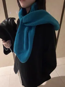 Détail de la maille d'une écharpe en laine bleue associée à un pull noir élégant