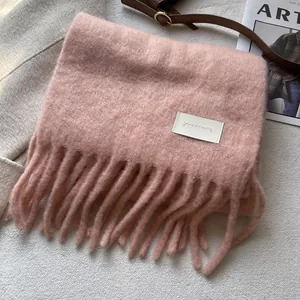 Detail of pink wool-like scarf featuring long fringe and a sewn-on brand label
