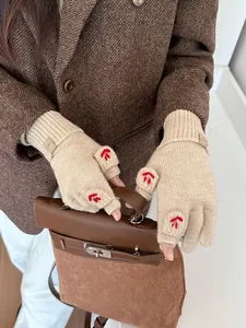 Detail of beige knitted gloves with red embroidery and elastic wrist cuffs for winter